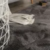 A close-up view of a plush gray rug with a folded blanket and a white basket. Anteprima dell’immagine prodotto