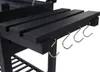 A close-up view of the side of a black charcoal grill, showing a wooden slatted shelf and three metal S-hooks hanging from it. Podgląd zdjęcia produktu