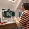 A person is on a video call with another person on an all-in-one computer. Produktbild-Vorschau