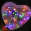 A heart-shaped box filled with colorful LED string lights. Produktbild-Vorschau