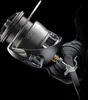 A close-up studio shot of a fishing reel against a black background. Náhled obrázku produktu