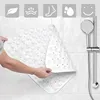 A person holding a white triangular shower mat in a bathroom. Voir les images du produit