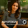 A woman is posing for a photo with a digital camera in the foreground, with text overlays. Produktbild-Vorschau