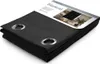 A folded black blackout curtain with metal eyelets is displayed on a white background. The packaging is partially visible at the top with product information and a lifestyle image. Produktbild-Vorschau