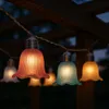 String lights with tulip-shaped bulbs hanging from a wooden structure at dusk. Produktbild-Vorschau