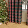 A Christmas tree decorated with ornaments and lights, next to plaid curtains and gift boxes on a wooden floor. Produktbild-Vorschau