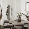 A dining area with a round table, chairs, and a decorative mirror on the wall. Produktbild-Vorschau