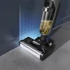 A close-up shot of a vacuum cleaner head with a dirty roller brush, positioned near a wall with a grid pattern. The vacuum's transparent tank shows collected dirt and liquid. Voir les images du produit