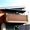 A modern building with a balcony featuring a brown privacy screen. Anteprima dell’immagine prodotto