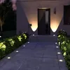 A pathway leading to a house entrance at night, illuminated by ground lights and wall lights. Produktbild-Vorschau