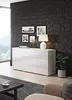 A modern living room with a white high-gloss sideboard against a dark brick wall, featuring framed pictures and a table lamp. Anteprima dell’immagine prodotto
