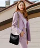 A woman wearing a purple suit and carrying a black handbag. Náhľad obrázku produktu