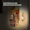 A cat walks past a wall-mounted night light with motion sensor, illustrating its range and detection angle. Náhled obrázku produktu