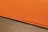 A close-up view of an orange rug on a wooden floor. Voir les images du produit