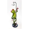 A figurine of a frog standing under a shower head, holding a pink sponge. Produktbild-Vorschau