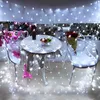 A decorated outdoor seating area with string lights, a table, chairs, and a Pink Panther plush toy. Náhled obrázku produktu