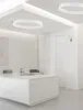 A modern, minimalist white kitchen with a central island and circular ceiling lights. Produktbild-Vorschau