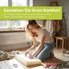 A woman is cutting a foam block on a wooden floor, surrounded by fabric and tools. Produktbild-Vorschau