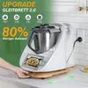 A white kitchen appliance, likely a food processor, is shown on a countertop with a wooden sliding board underneath. The appliance is plugged in and a hand is shown interacting with it. The background features kitchen cabinets and a tiled backsplash. Produktbild-Vorschau
