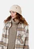 A woman wearing a cream-colored fuzzy hat and a plaid jacket. Produktbild-Vorschau