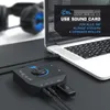 A black USB sound card is connected to a laptop, with headphones in the background. Produktbild-Vorschau