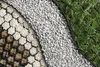 A close-up, overhead view of a garden border system, showing three distinct sections: a honeycomb grid filled with soil and small stones, a section of white gravel, and a section of artificial grass. Produktbild-Vorschau