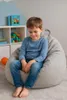 A young boy sits on a beanbag chair in a child's room. Produktbild-Vorschau