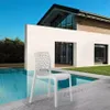 A white designer chair is placed on a patio next to a swimming pool, with a modern house in the background. Produktbild-Vorschau