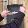 A person is putting mail into a gray mailbox mounted on a wooden wall. Náhľad obrázku produktu