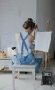 A woman is painting in an art studio, with a heater in the foreground. Produktbild-Vorschau