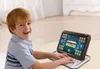 A young boy is smiling and using a toy tablet that resembles a laptop. Produktbild-Vorschau