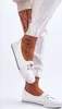 A close-up shot of a person's feet wearing white sneakers. Voir les images du produit