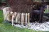 A garden scene with a wooden picket fence, decorative deer, and a lantern. Produktbild-Vorschau