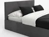 A close-up view of a bed with a upholstered headboard and frame, featuring black pillows and white bedding. Produktbild-Vorschau