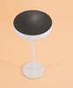 A white table lamp with a black solar panel top on a light peach background. Produktbild-Vorschau