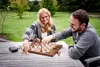 A couple playing chess outdoors at a wooden table. Podgląd zdjęcia produktu