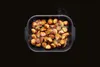 A roasting pan filled with roasted potatoes and herbs, with steam rising. Produktbild-Vorschau