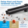 A black shower head with mineral beads scattered on a tiled surface. Produktbild-Vorschau