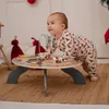 A baby is playing with a wooden activity table on a rug. Podgląd zdjęcia produktu