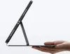 A hand holding a black iPad case with a stand, against a white background. Produktbild-Vorschau