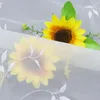 A close-up view of a sheer white curtain with embroidered white leaves and branches, partially covering two artificial sunflowers. Produktbild-Vorschau