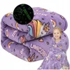A folded purple blanket with a unicorn pattern is shown, with a young girl wrapped in a similar blanket next to it. Náhled obrázku produktu