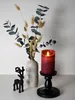 A red LED candle in a black candle holder sits next to a vase of dried flowers and eucalyptus, with a small black deer figurine to the left. Podgląd zdjęcia produktu