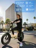 A man riding an electric bicycle on a street with palm trees and buildings in the background. Produktbild-Vorschau