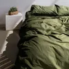 A bed with green bedding is shown in a room with natural light casting shadows. Podgląd zdjęcia produktu
