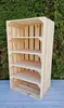 A wooden crate shelf unit is displayed outdoors against a backdrop of green foliage and a gray surface. Produktbild-Vorschau