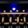 A close-up view of a wine cooler with several bottles on wooden shelves, illuminated by blue LED lights. Produktbild-Vorschau