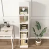A tall, narrow white bookshelf filled with books and decorative items, placed next to a desk with a lamp and a laptop. Podgląd zdjęcia produktu