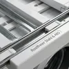 Close-up view of a washing machine or dryer stacking frame, showing metal rails and white plastic components. Podgląd zdjęcia produktu