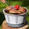 A person is grilling steaks and vegetables on a portable grill outdoors. Produktbild-Vorschau